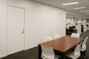 Temporary modular wall system in office setting, featuring a wooden table and chairs, illustrating efficient workspace containment during renovations.