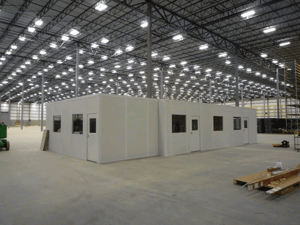 Modular in-plant office under construction inside warehouse with temporary wall containment